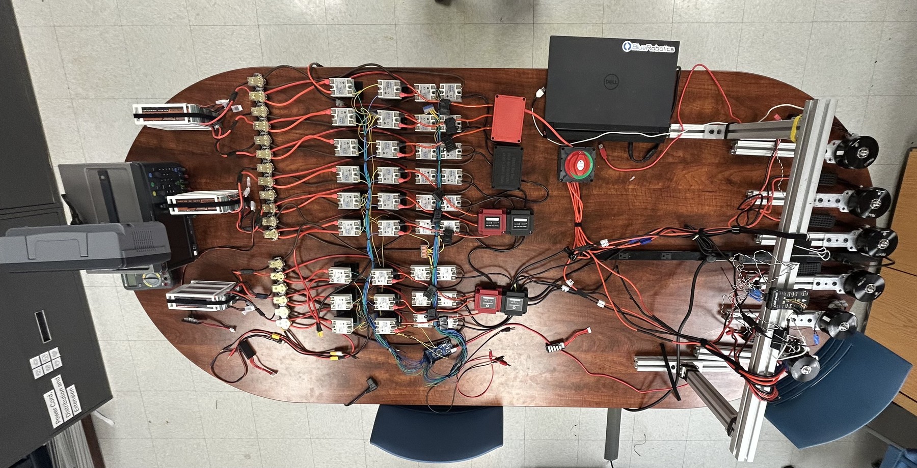 Top-down view of the full bench prototype: six motors on rails, the solid-state-relay switching network, and the three-Arduino monitoring stack