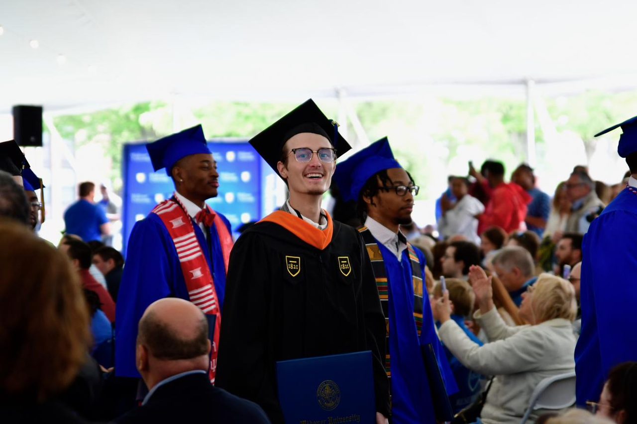 Cole walking with his diploma in black robes at his master's graduation